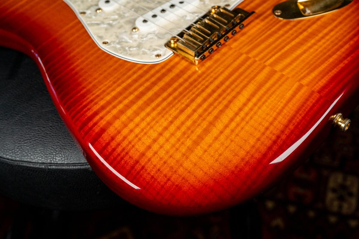 Close-up of the guitar's lower body, showing a vibrant orange-red flame top finish, gold hardware, and a pearloid pickguard.