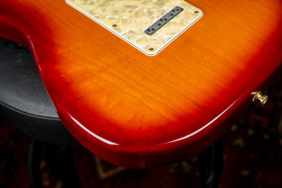 Close-up of the guitar's lower body, showing the glossy sunburst finish, pearloid backplate, and gold output jack.