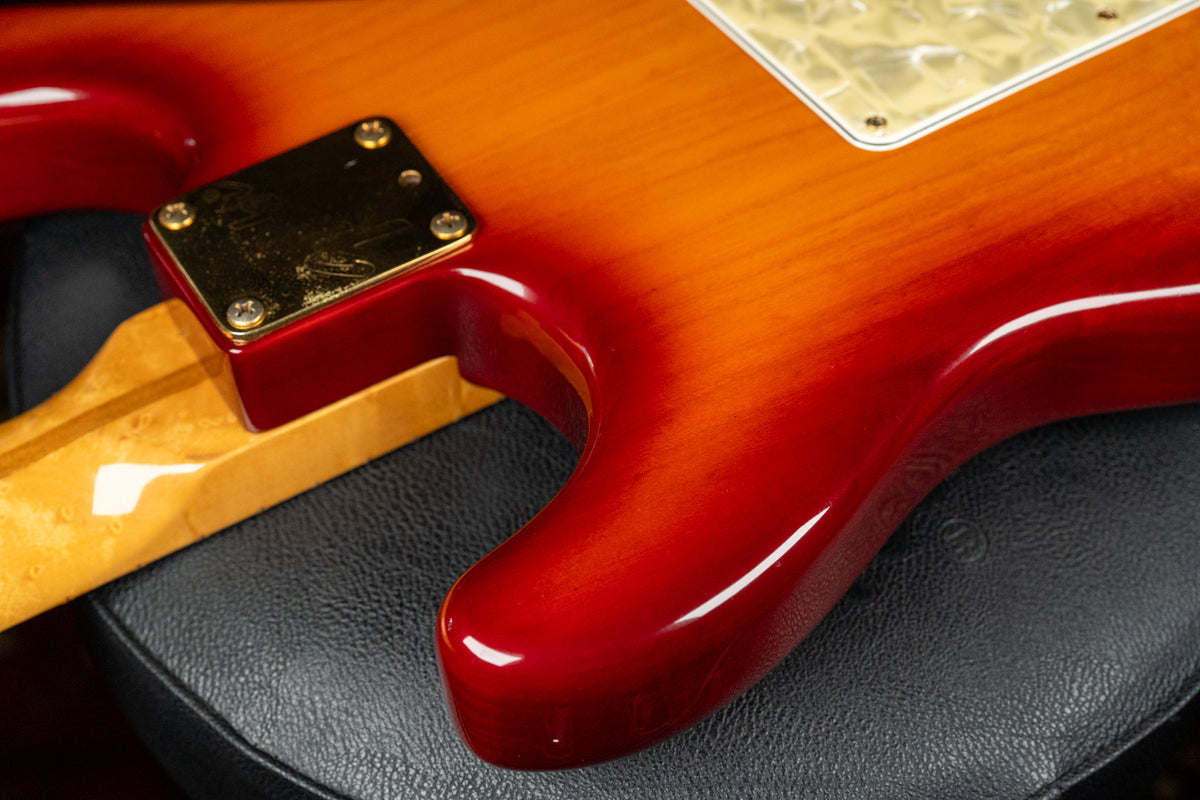 Close-up of the guitar's lower horn and neck joint, showing the glossy cherry sunburst finish, gold neck plate, and light maple neck.