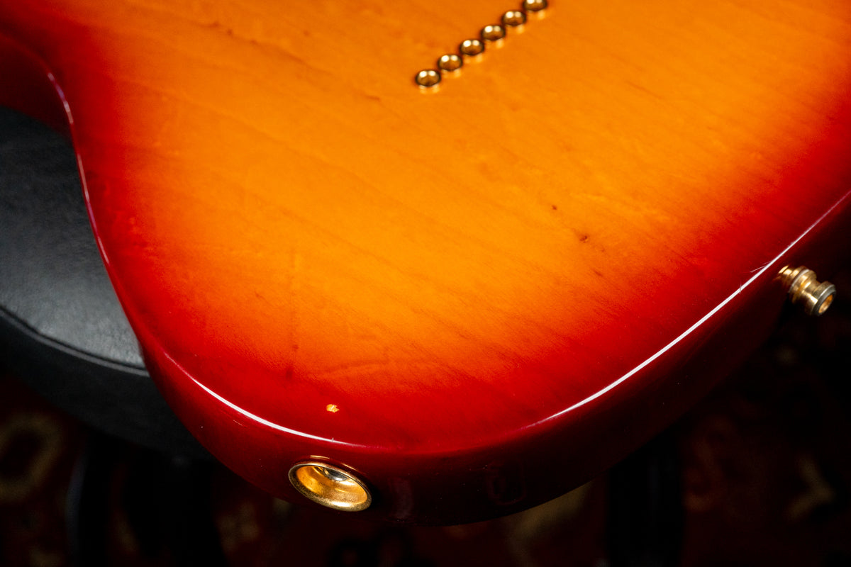 Close-up of the guitar's lower bout, showing the sunburst finish, gold string ferrules, and output jack, with minor finish wear.