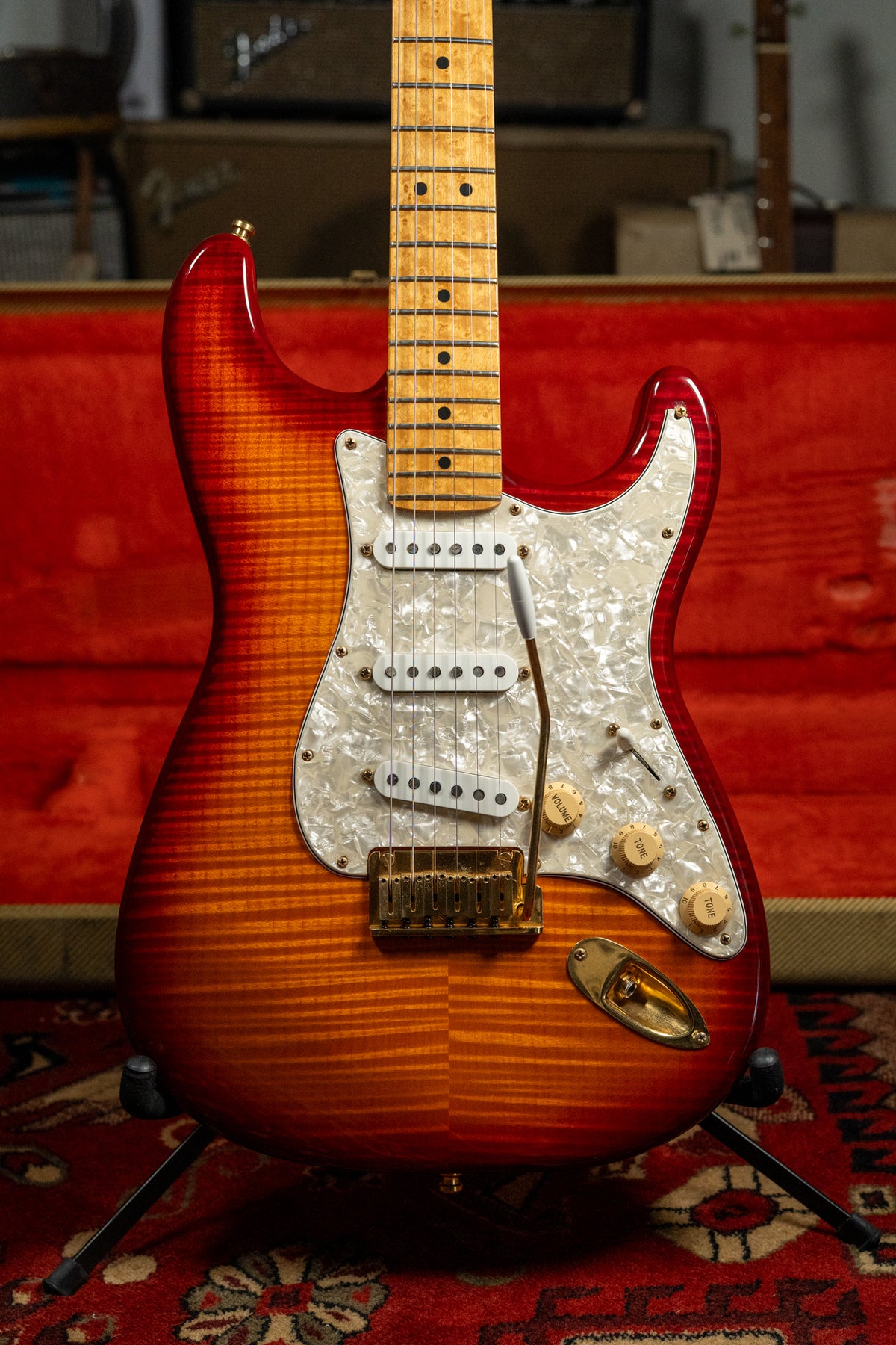 A cherry sunburst electric guitar with a flame maple top, gold hardware, pearloid pickguard, and a maple fretboard.
