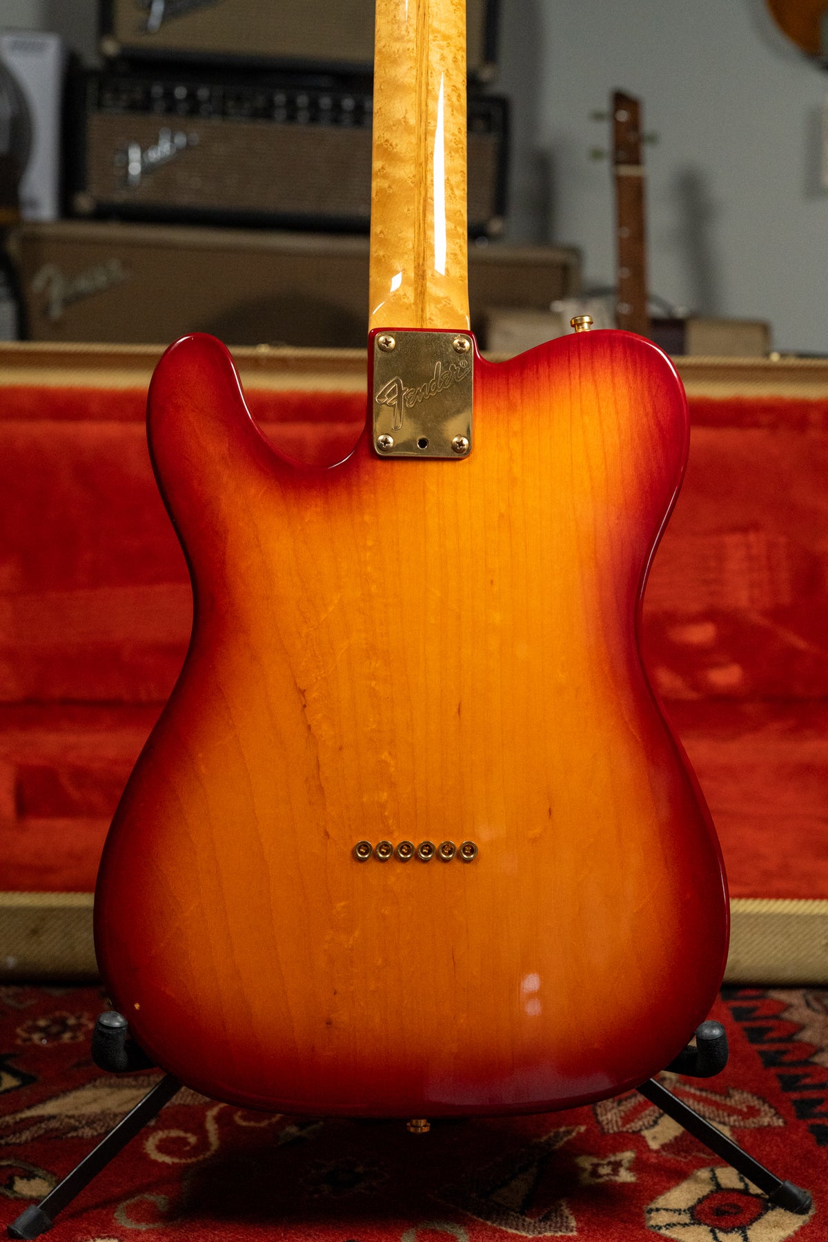 The back of a Telecaster-style guitar in a cherry sunburst finish, with a maple neck and gold hardware.