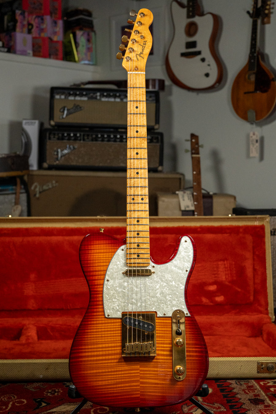 Full-length view of a flame-top Telecaster in a cherry sunburst finish, with a pearloid pickguard and gold hardware.