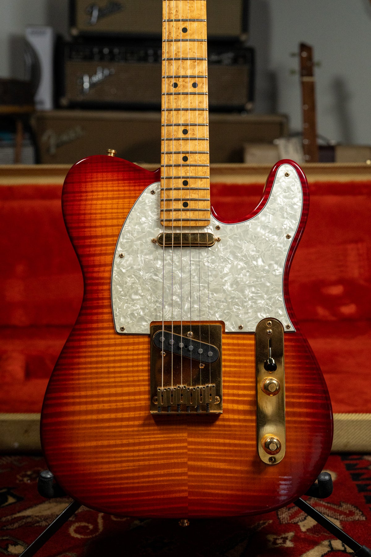 Close-up of a sunburst flame-top Telecaster with a pearloid pickguard, gold hardware, and a birdseye maple fretboard.