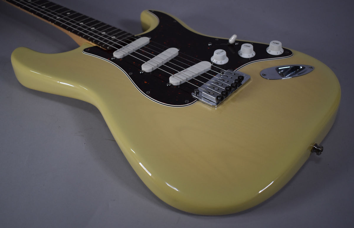 Angled view of a vintage blonde Stratocaster, showing its glossy body, tortoiseshell pickguard, three white pickups, and chrome hardware.