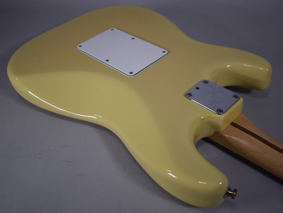 The back of a glossy vintage blonde Stratocaster body, showing the white tremolo cover and chrome neck plate.