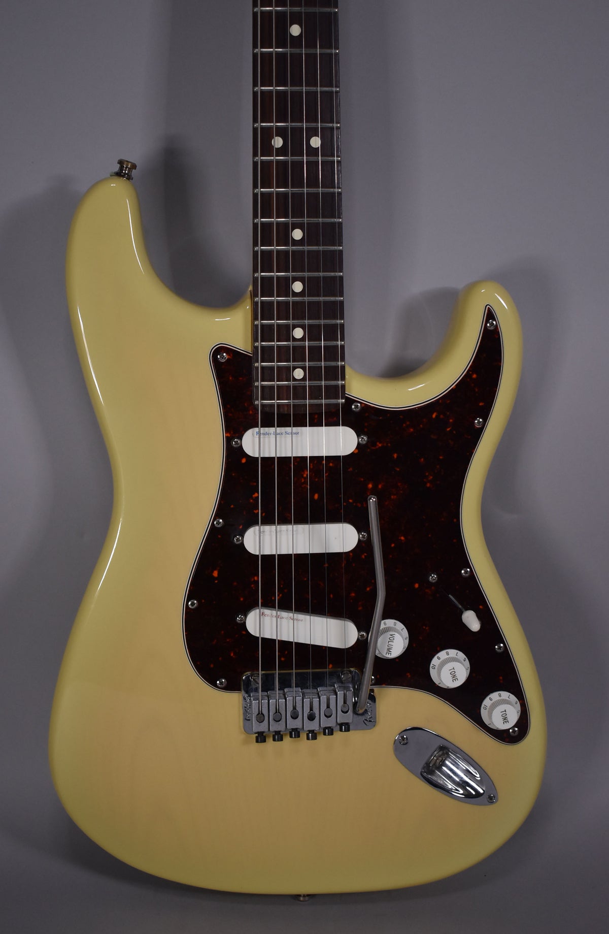 Full front view of a vintage blonde Stratocaster with a tortoiseshell pickguard, three white single-coil pickups, and a tremolo bridge.