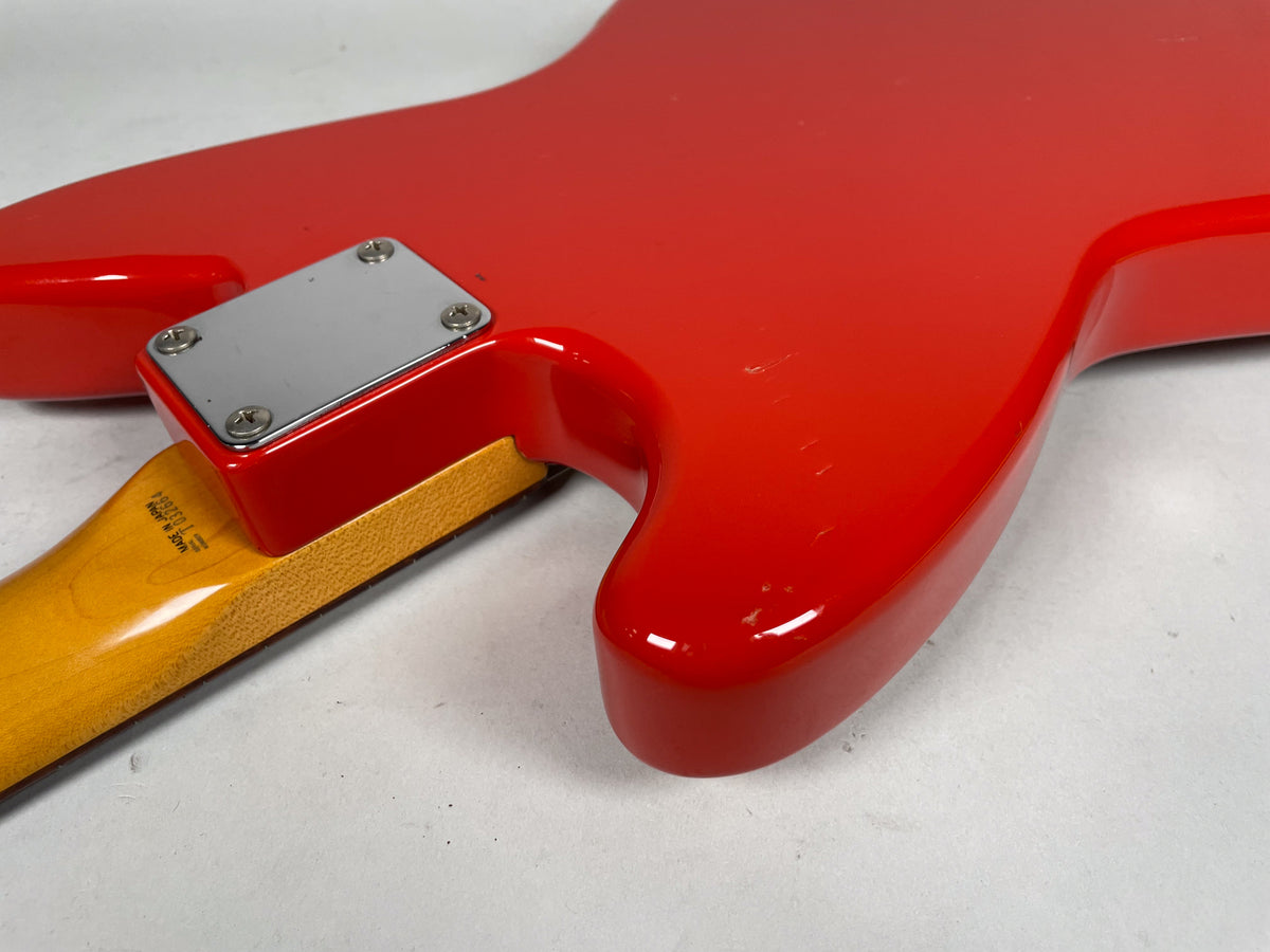 The Fiesta Red guitar body, with a chrome neck plate, shows several small dings and scratches on its glossy finish.