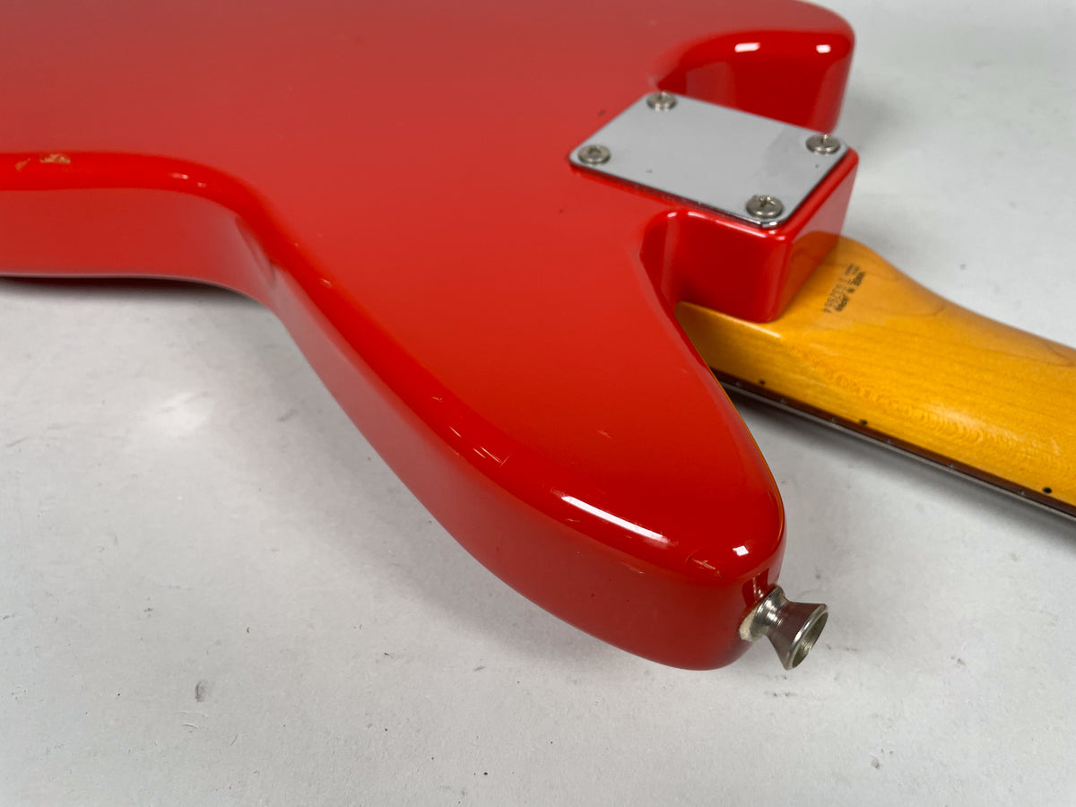 Close-up of the Fiesta Red guitar body's lower bout, showing the chrome neck plate, maple neck heel, and output jack.