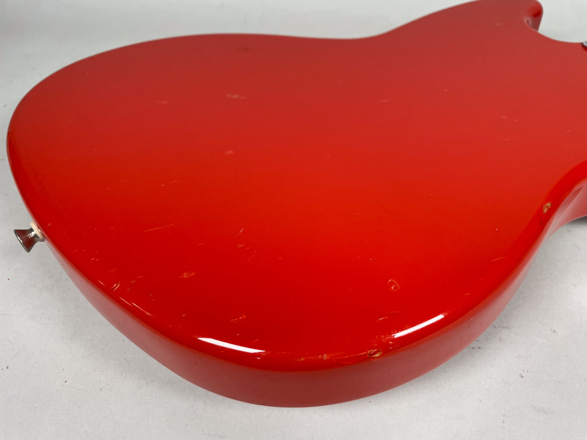 The Fiesta Red guitar body's back shows numerous scratches, dings, and paint chips, especially along the lower edge.