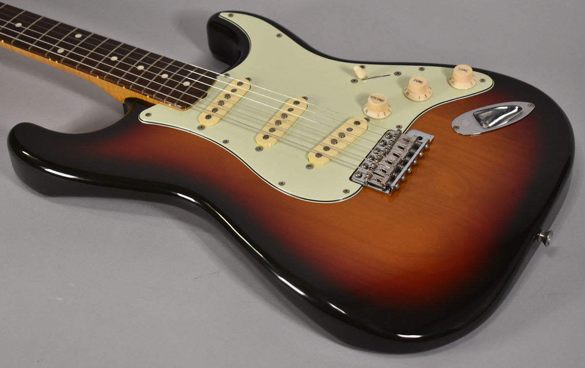 Right-side view of a sunburst electric guitar with a mint green pickguard, three cream single-coil pickups, and chrome hardware.