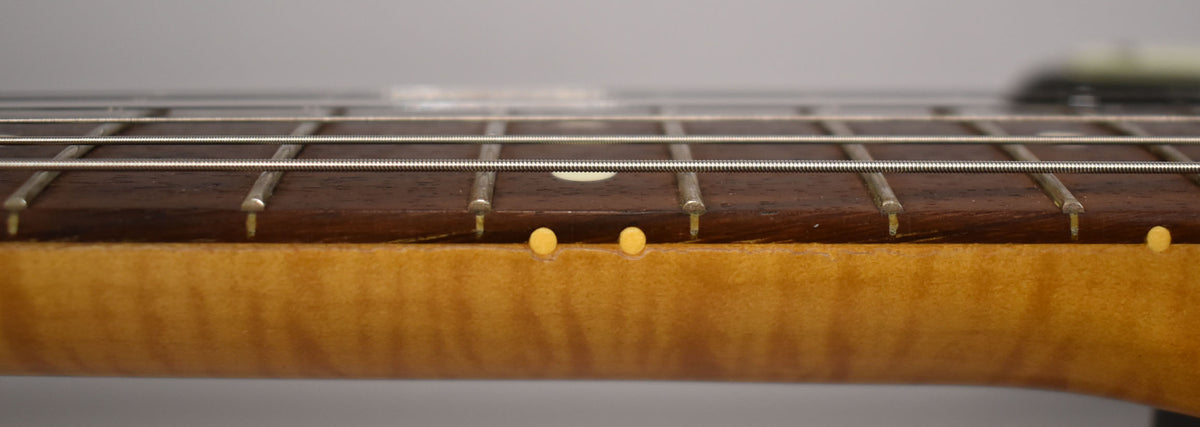 Close-up of the dark rosewood fretboard and maple neck, showing light wear on the frets and side dots.
