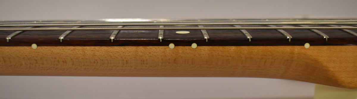 Close-up of the dark rosewood fretboard and light maple neck, showing white dot inlays and fret wear.