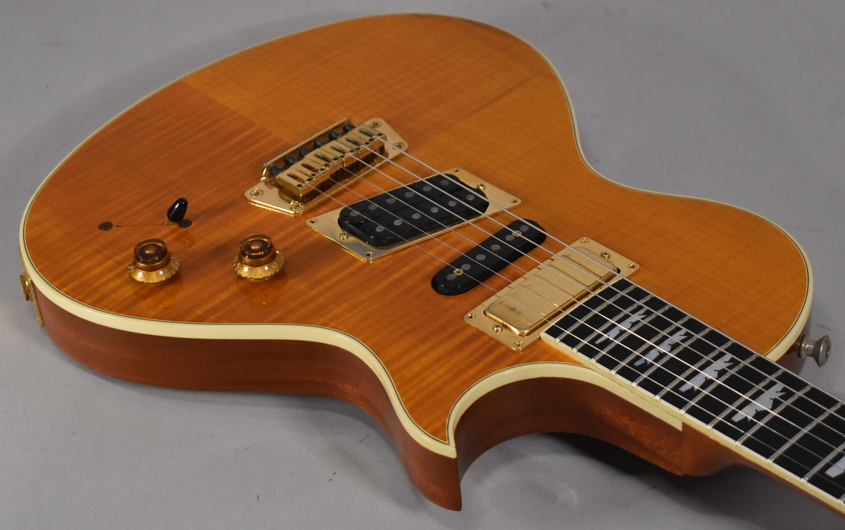 Upper body of a transparent amber guitar with gold hardware, two humbuckers, two control knobs, and a bird inlay fretboard.