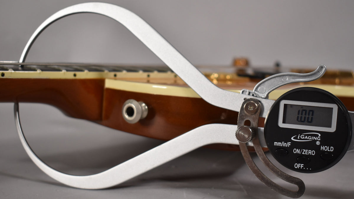 Close-up of the guitar's amber-finished neck and fretboard, with a digital caliper measuring the fret height at 1.00mm.
