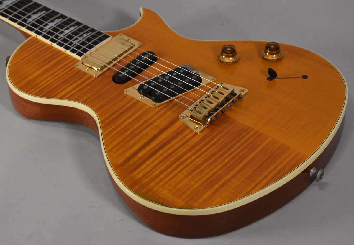 The amber flamed maple body, with gold hardware and cream binding, shows light wear around the two control knobs.