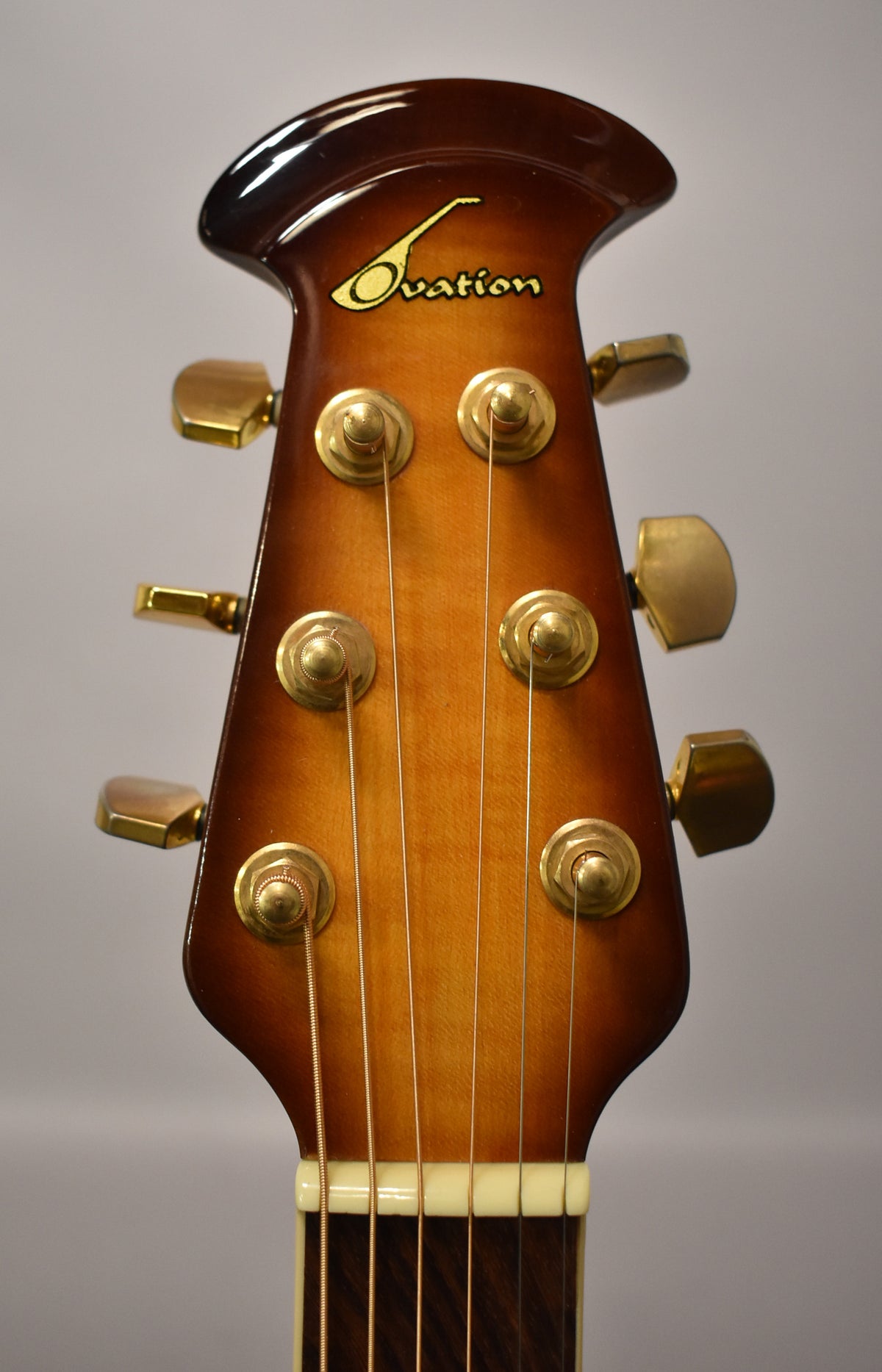 Close-up of the sunburst headstock with gold tuners, showing light wear on the finish and some tarnishing on the hardware.