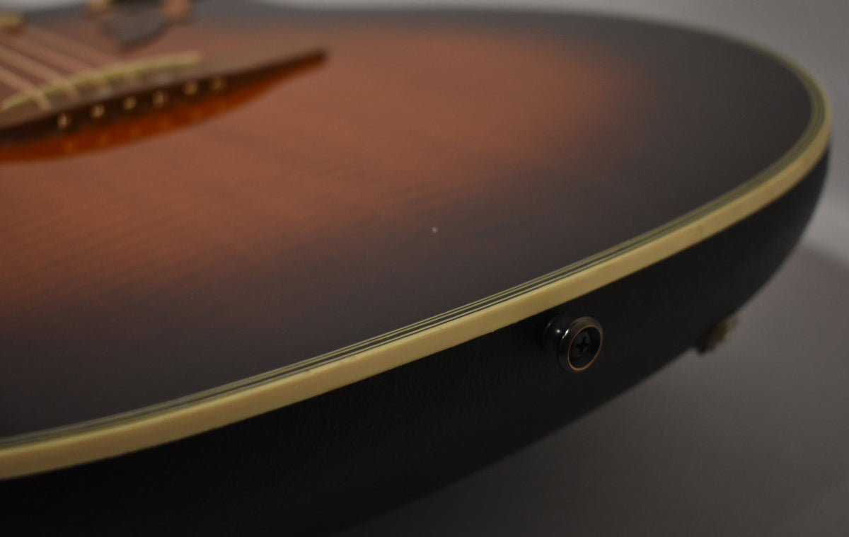 Close-up of the sunburst top and black bowl back, showing the cream binding and a dark metal endpin jack.