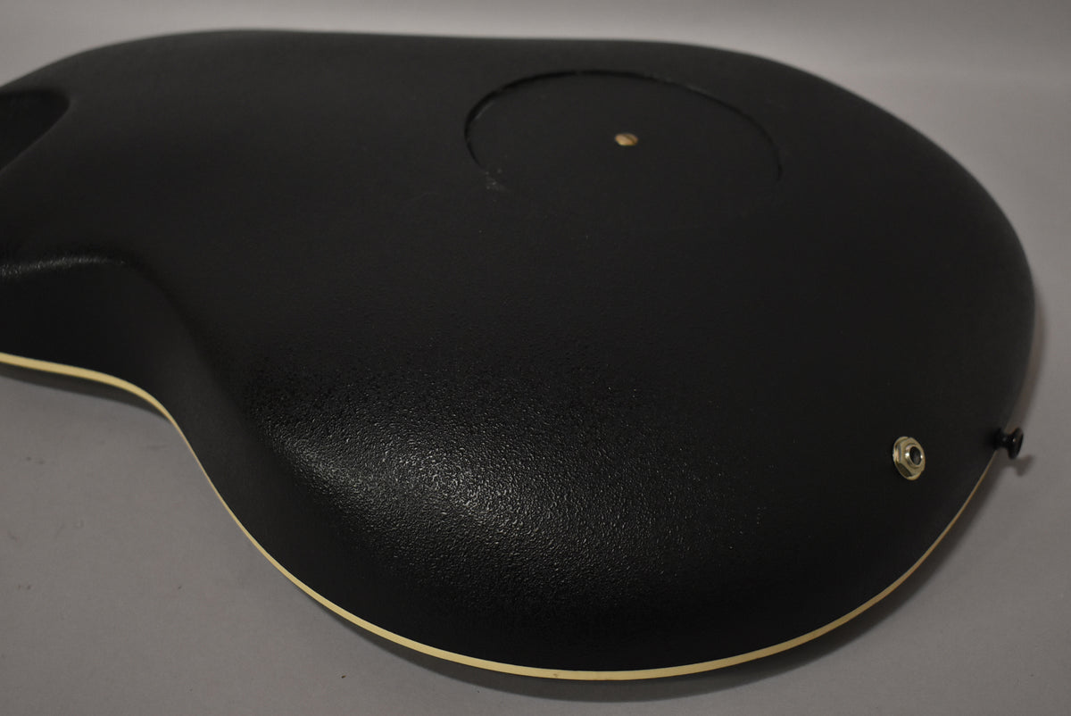 The guitar's textured black Lyrachord back and bowl are angled, showing the cream binding and endpin jack.