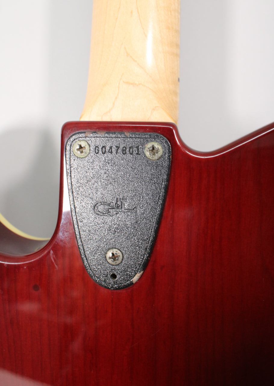 Close-up of the guitar's neck heel and body in a sunburst finish, showing the neck plate with serial number G047801 and wear.