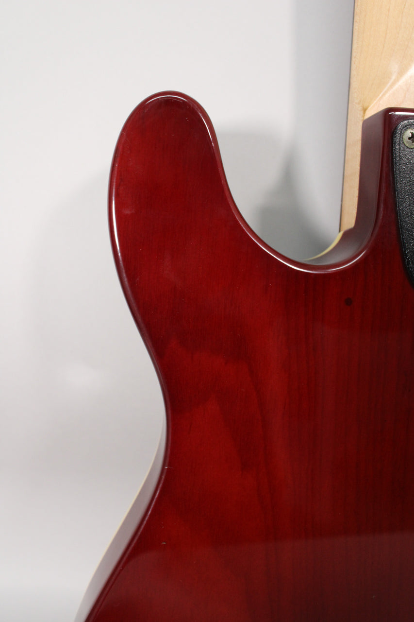 Close-up of the guitar's upper horn and cutaway, showing the deep red sunburst finish and a small dark mark on the body.
