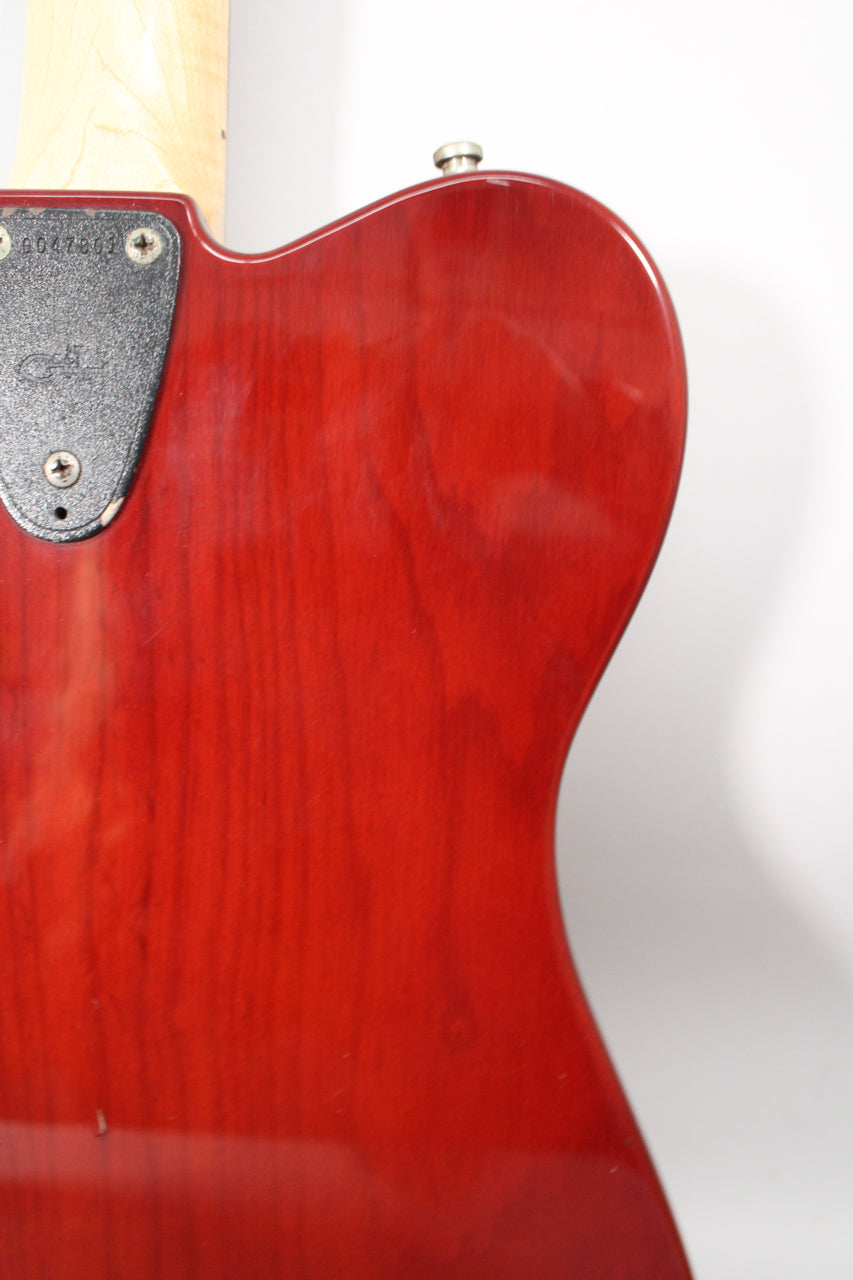 The guitar's upper body, in a glossy red sunburst finish, shows a chrome strap button and a black neck plate with visible serial numbers.