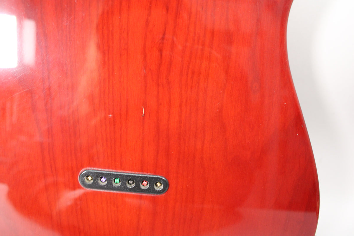 The back of the guitar's sunburst body, showing the string-through ferrules and light surface scratches on the glossy finish.