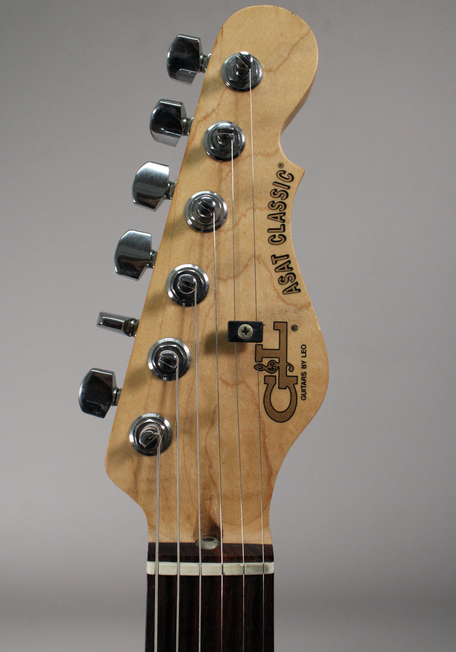 Close-up of the light wood headstock with six chrome tuners, a string tree, and a dark fretboard.