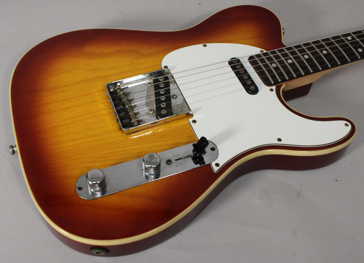 Close-up of the sunburst body, showing the white pickguard, chrome bridge, control plate with two knobs, and a black switch.