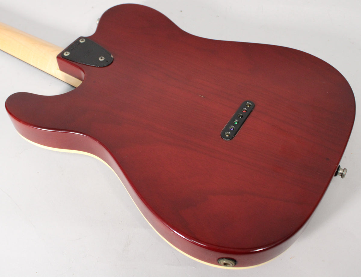 The back of the sunburst guitar body, showing the string-through ferrules, neck plate, and output jack, with light wear.