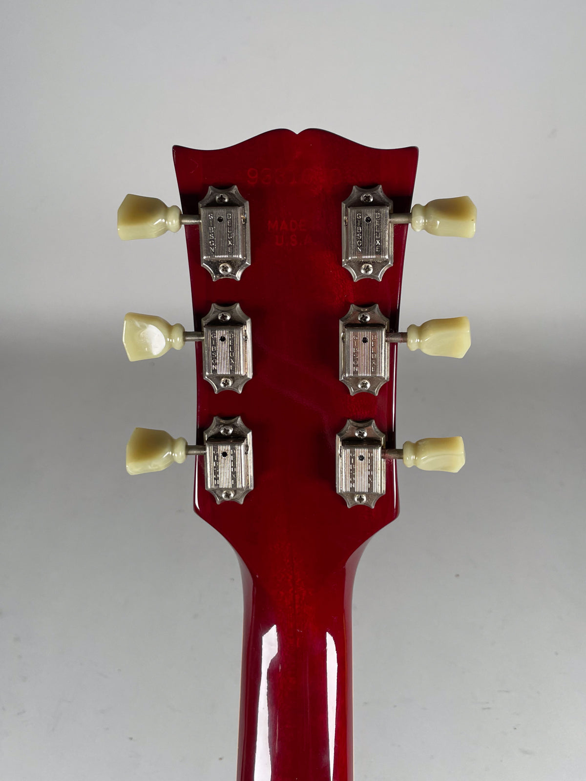 Rear view of the cherry red headstock and neck, showing six cream-buttoned tuners with chrome housings.