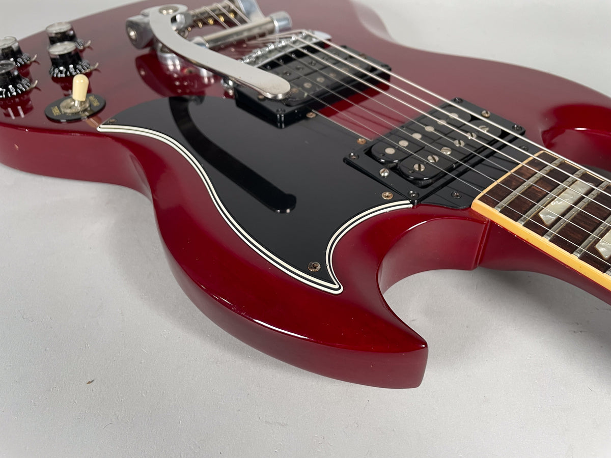 Close-up of the cherry red body, showing the black pickguard, two humbuckers, Bigsby, and four control knobs.