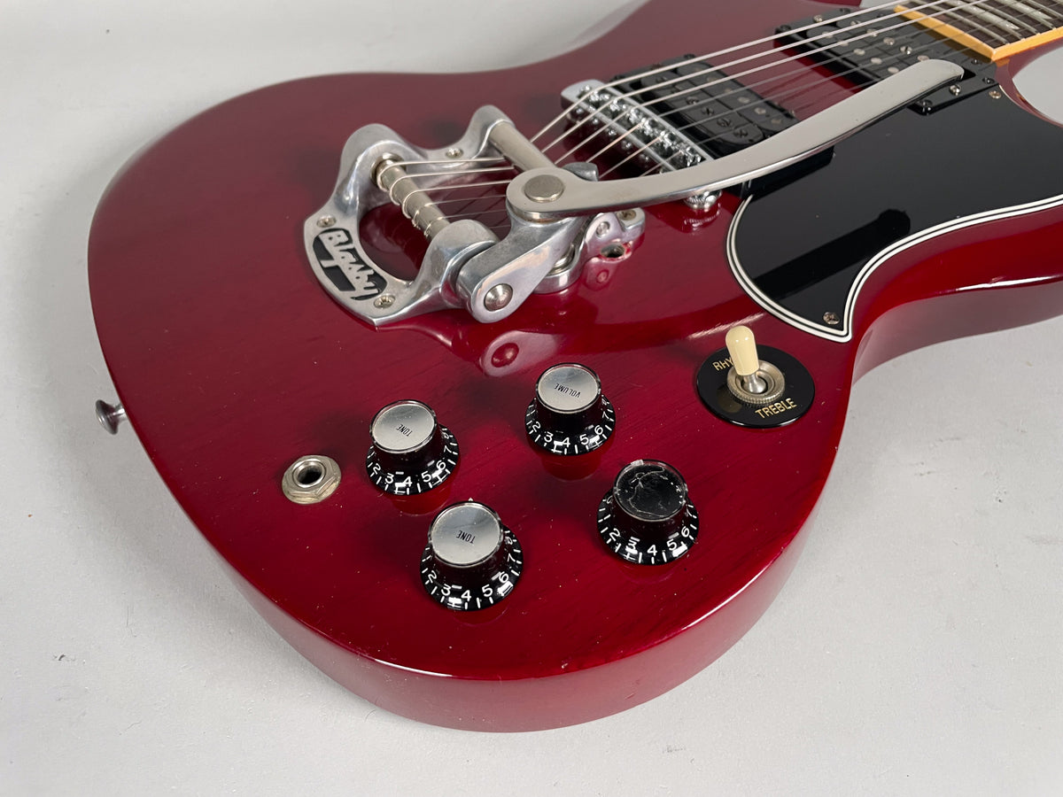 Close-up of the cherry red body, showing the Bigsby vibrato, black pickguard, four black control knobs, and cream toggle switch.