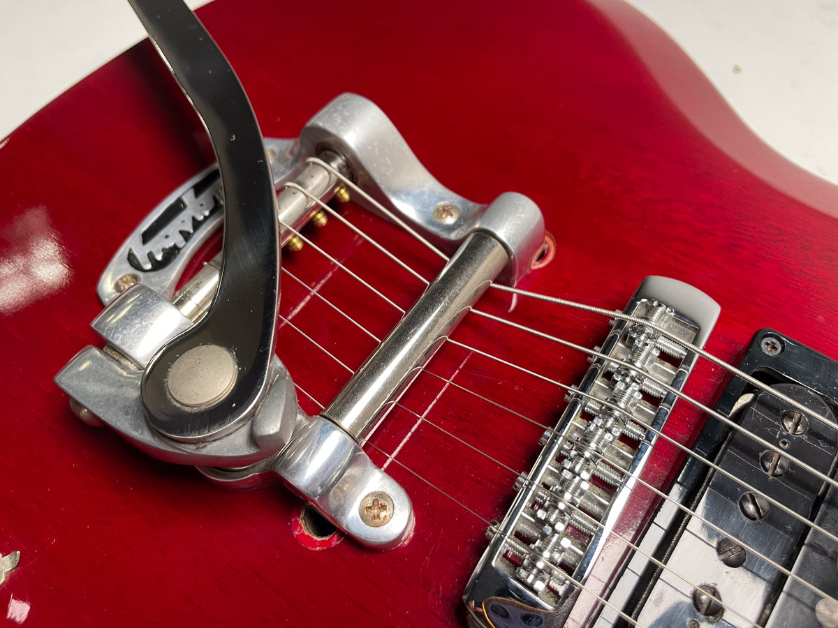 Close-up of the cherry red body, showing the Bigsby vibrato and bridge with some wear and a visible screw hole.