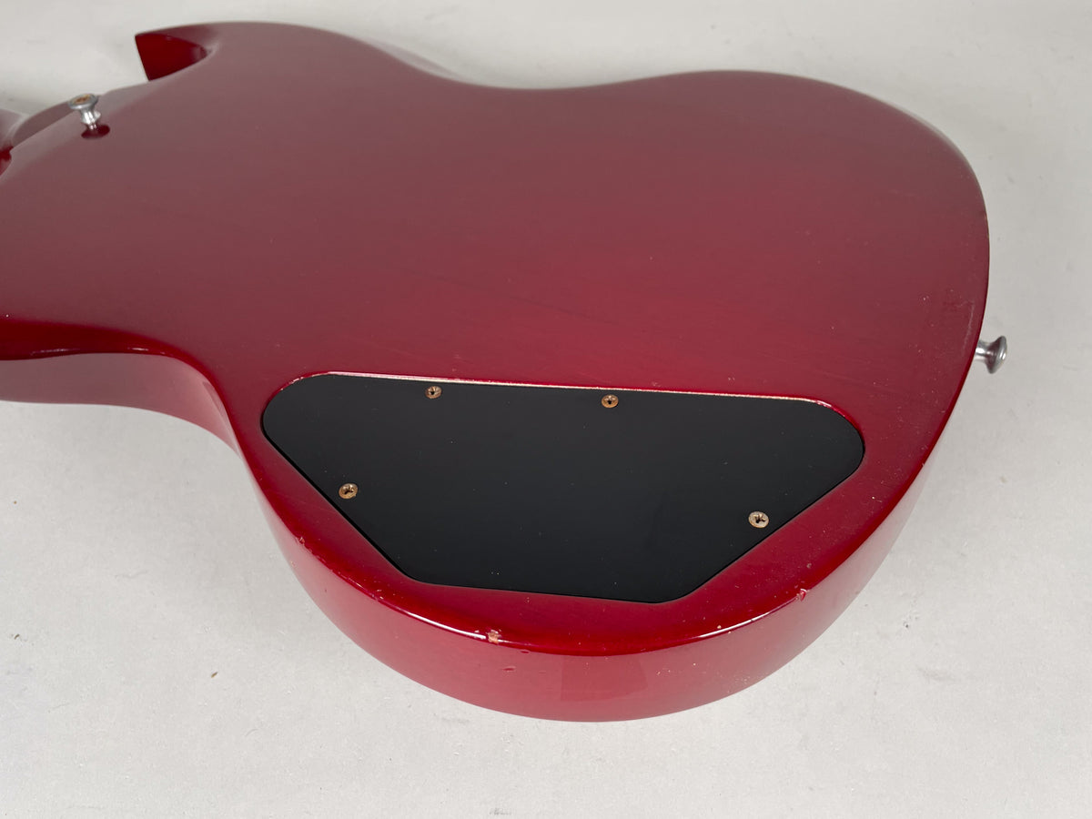 The cherry red SG's back shows a black control cavity cover, light surface scratches, and a small chip on the lower bout edge.