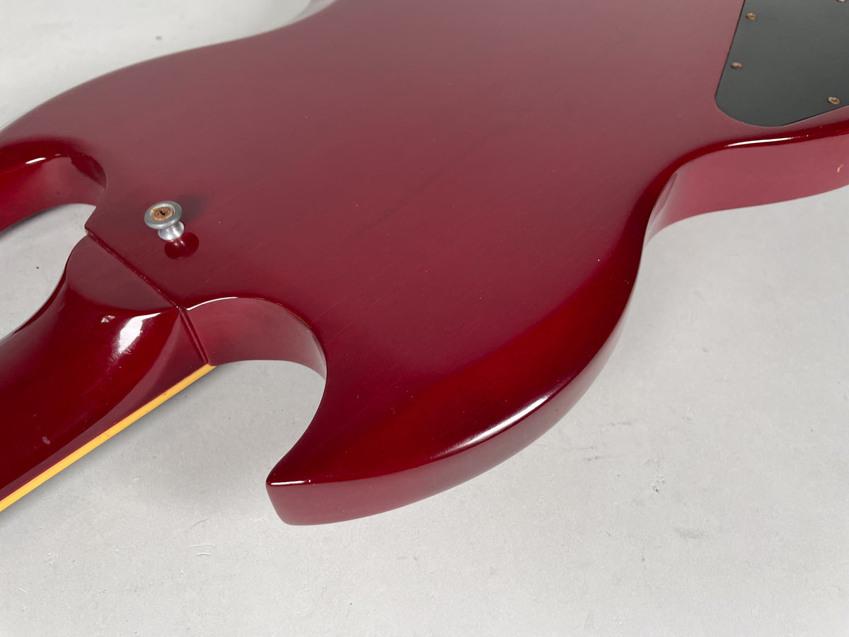 The back of the cherry red SG body, showing the neck joint, strap button, and control cavity cover, with minor surface wear.