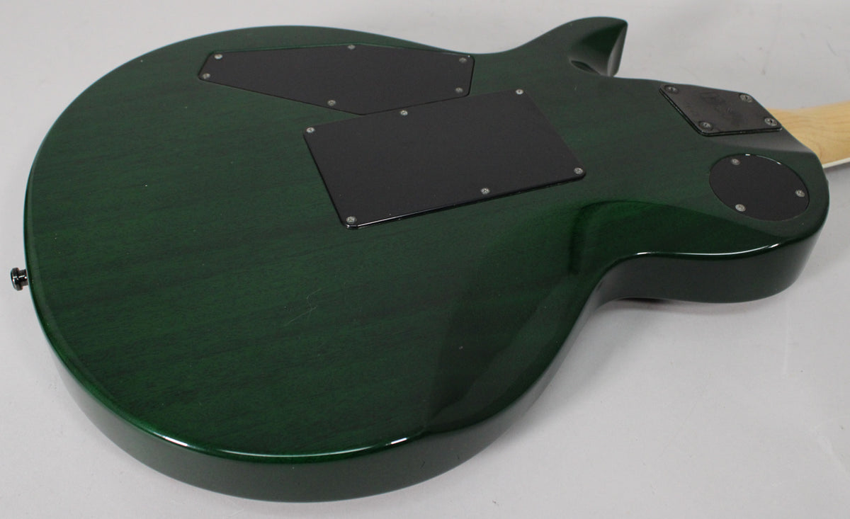 The back of the dark green guitar shows three black control cavity covers, a strap button, and light surface scratches.
