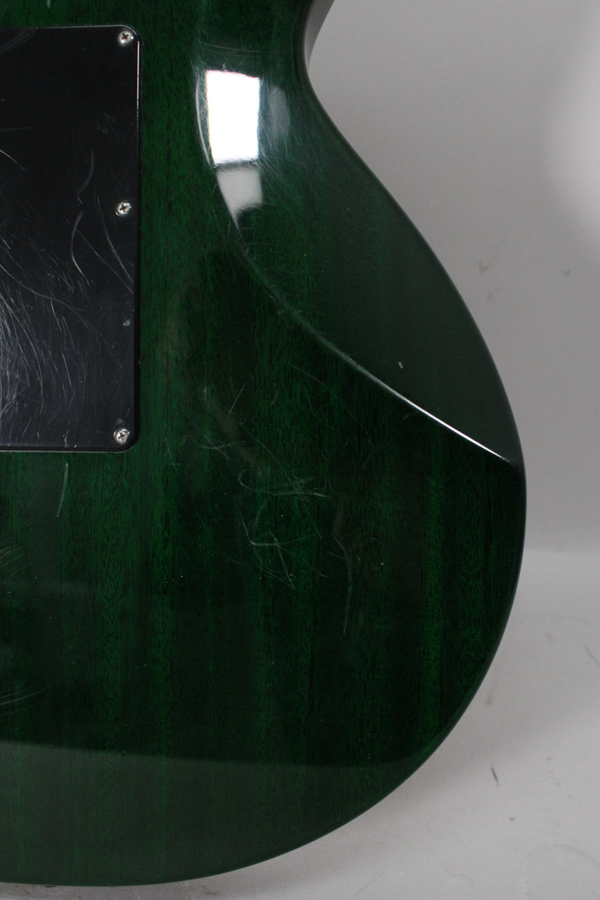 Close-up of the guitar's dark green back, showing many light scratches and a black control cavity cover with more scratches.
