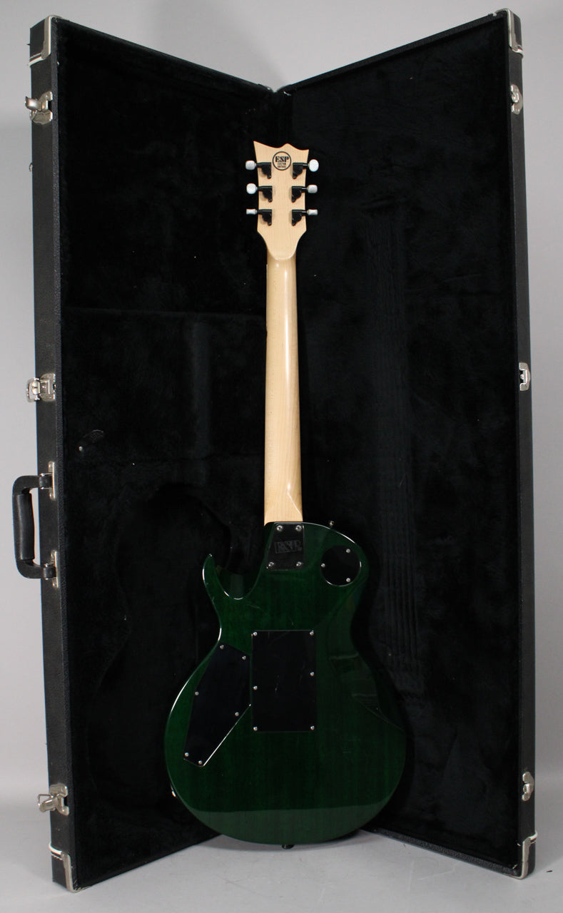 The back of a translucent green electric guitar with a light wood neck and headstock, resting in an open black hard case.