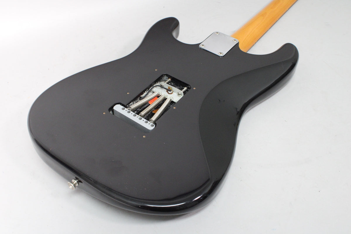 The black guitar's back shows the tremolo spring cavity with springs, a chrome neck plate, and a strap button on the lower bout.