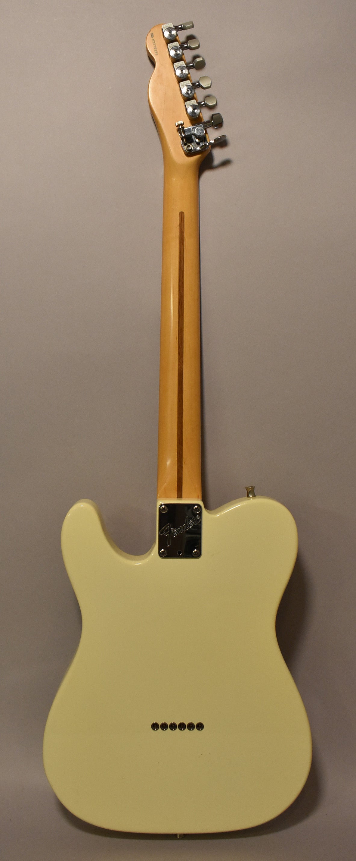 The back of an Olympic White Telecaster, showing the light maple neck, chrome tuners, neck plate, and string-through-body ferrules.