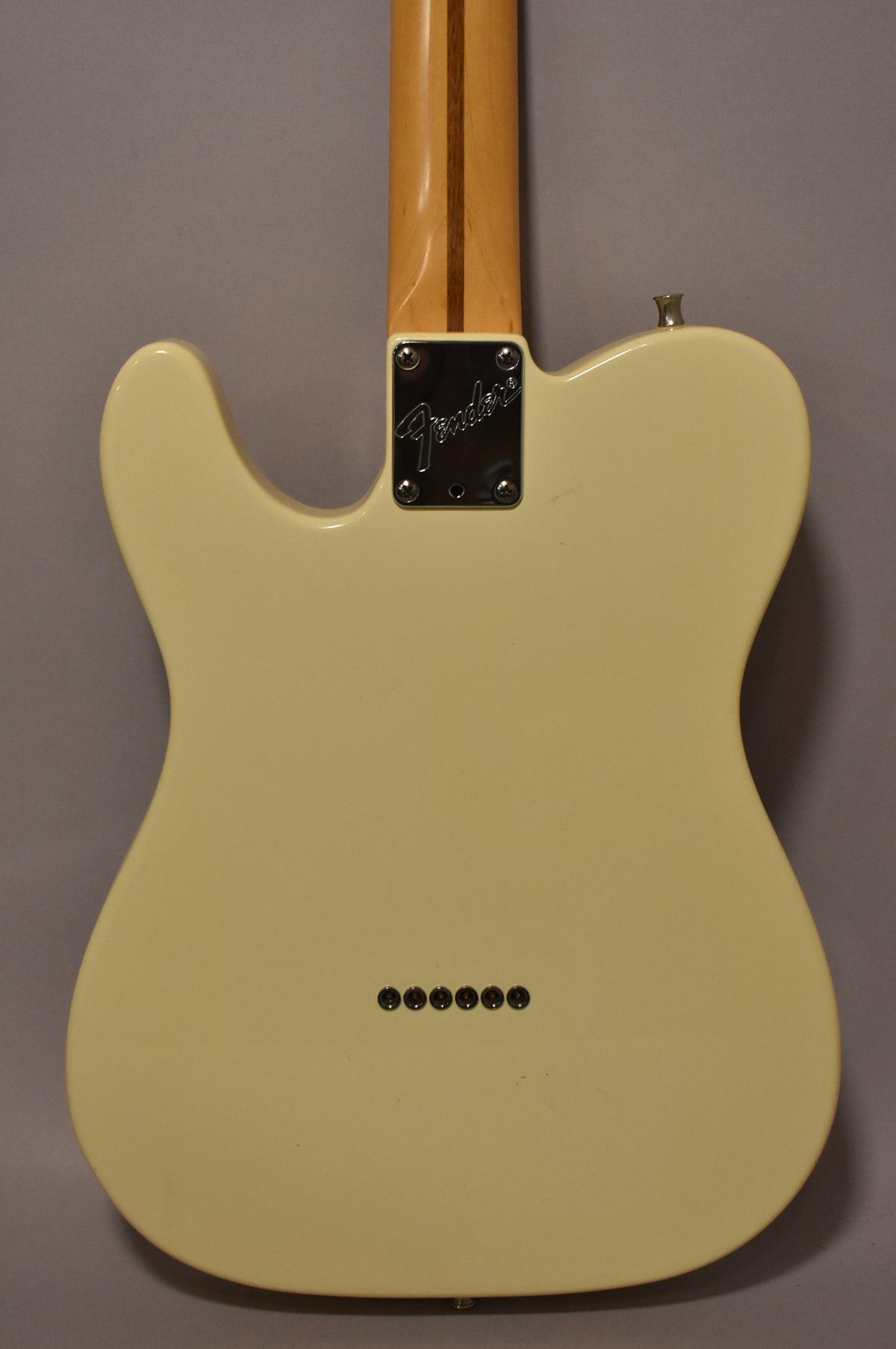 The back of an Olympic White Telecaster, showing the neck plate, string-through-body ferrules, and a light-colored maple neck.