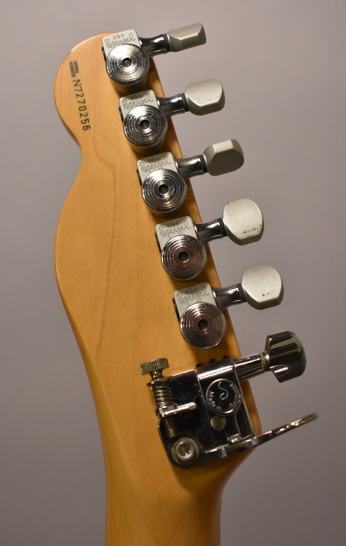Close-up of the guitar's headstock from behind, showing six chrome locking tuners with off-white buttons and a string tree.
