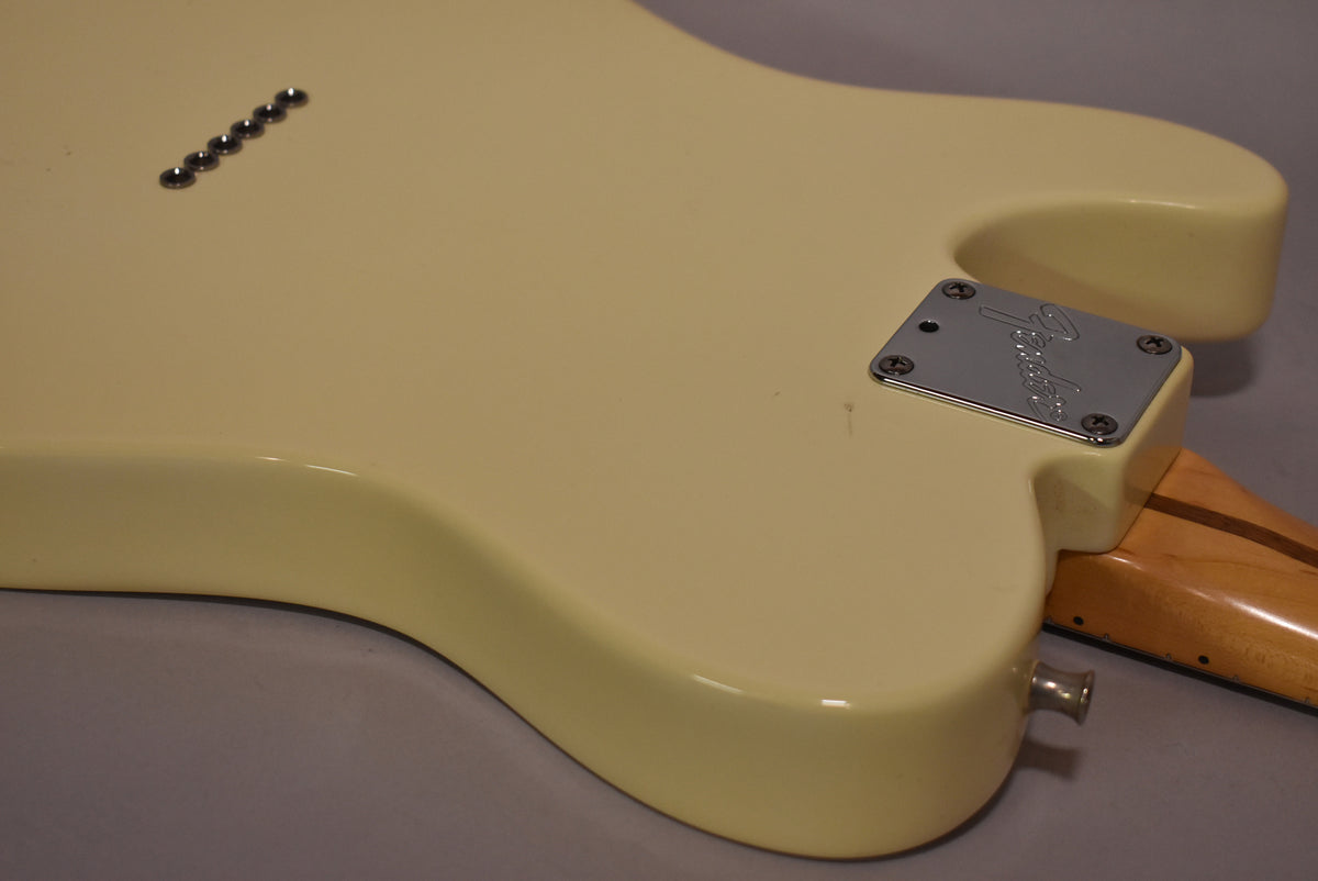 The back of an Olympic White Telecaster body, showing the chrome neck plate, string ferrules, and output jack, with light surface wear.