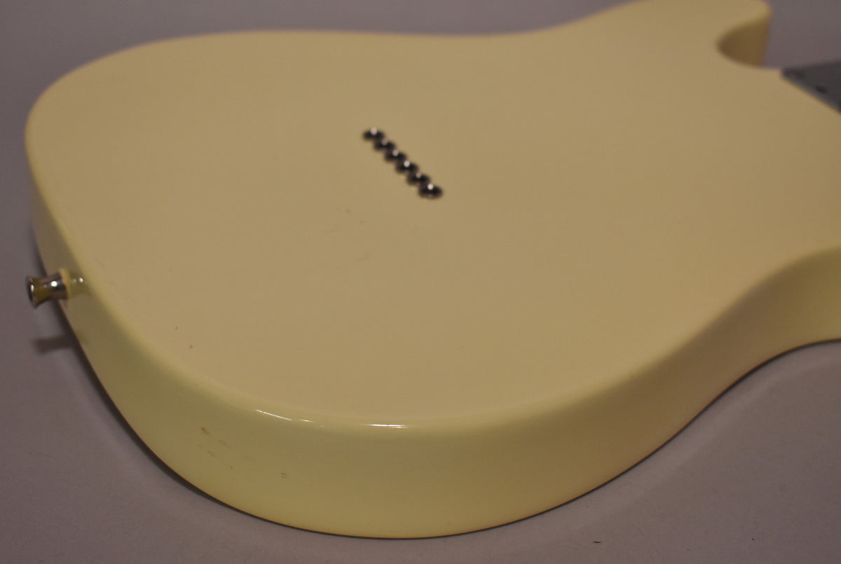 The back of an Olympic White Telecaster body, showing string-through ferrules, output jack, and light wear on the lower bout.