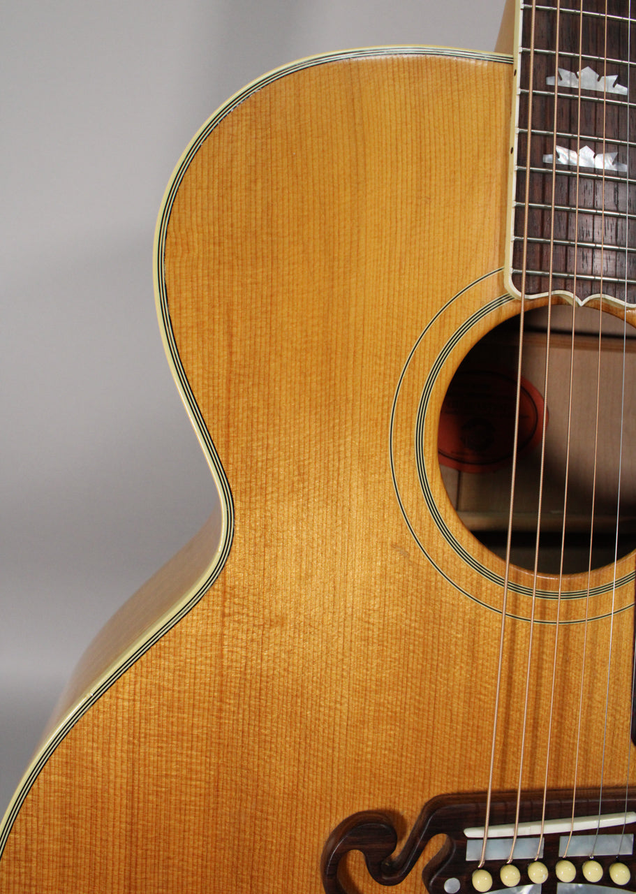 Close-up of the natural finish acoustic guitar's upper bout, soundhole, and part of the fretboard with mother-of-pearl inlays.