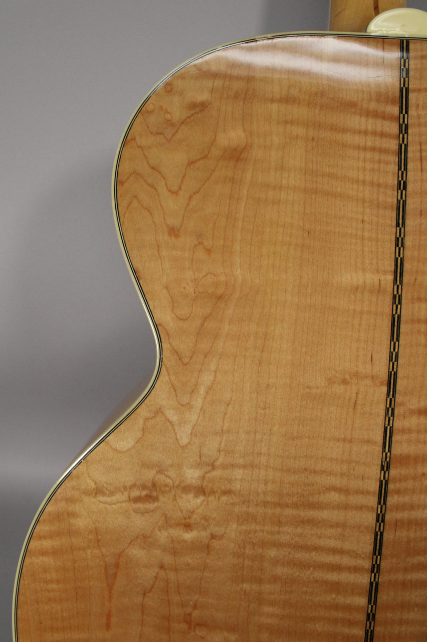 The guitar's light brown, figured maple back is shown from the upper bout, with a checkered center strip and cream binding.