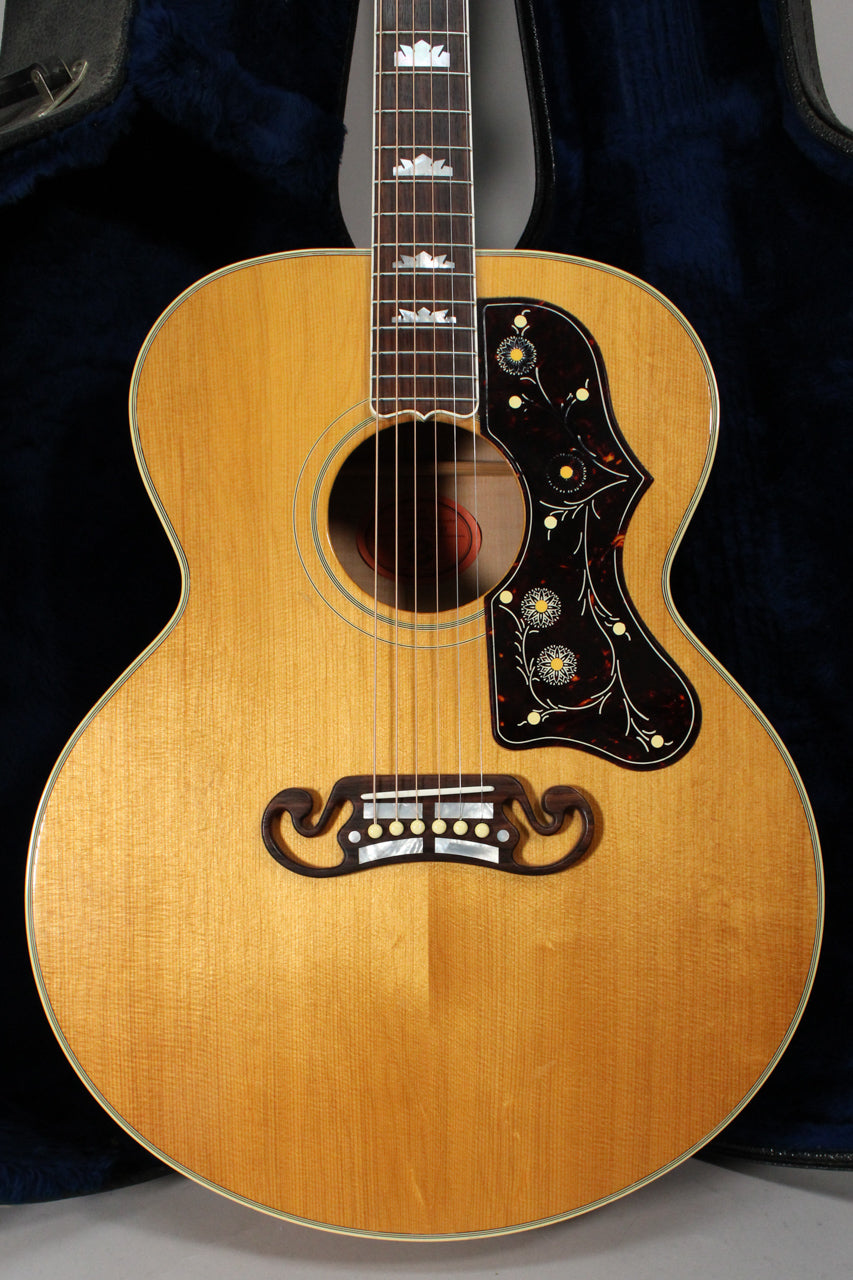 Full front view of a natural finish acoustic guitar with a dark tortoiseshell pickguard featuring floral designs.