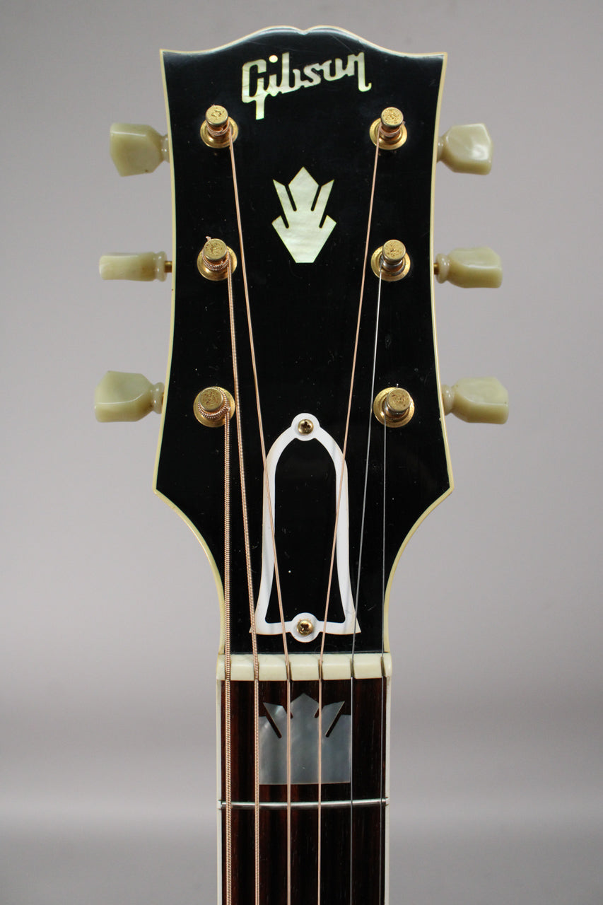 The black headstock, with a mother-of-pearl crown inlay, has six cream tuners and a bell-shaped truss rod cover.