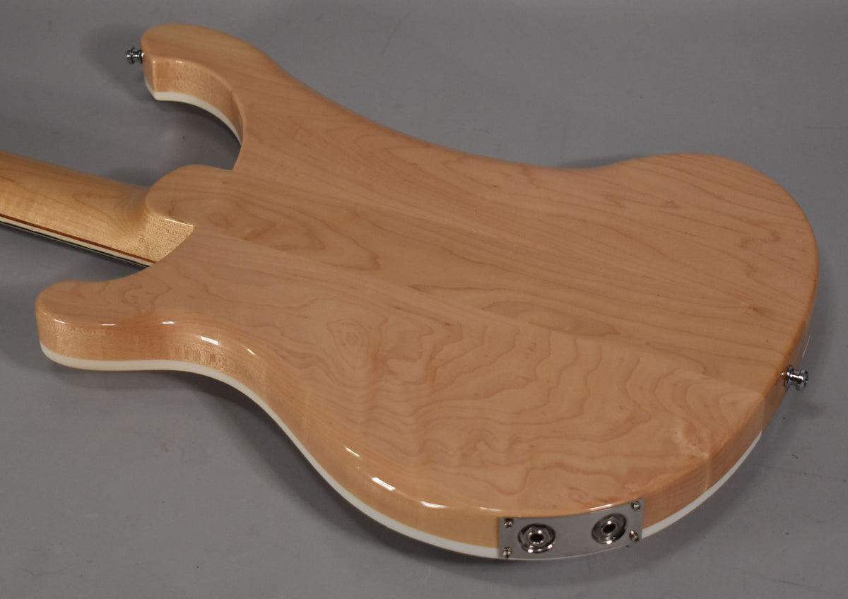 The back of a light maple bass with white binding, showing the neck joint, two output jacks, and a strap button.